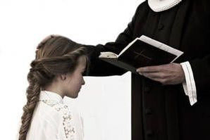 En præst er ved at konfirmere en pige